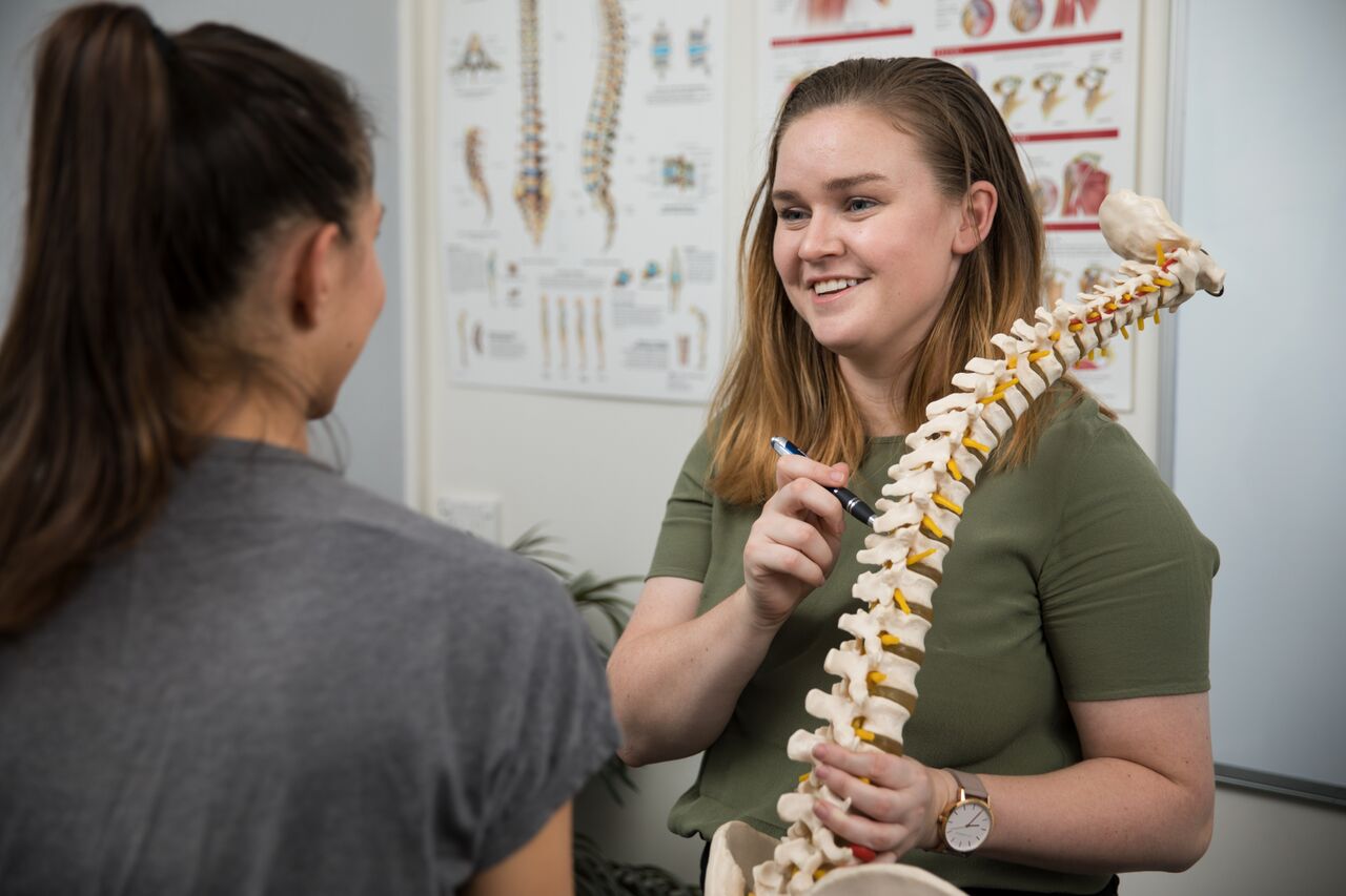 In this picture, North Ryde Physiotherapist Isabel Armsworth is demonstrating how neck pain can often be associated with your work place set up .